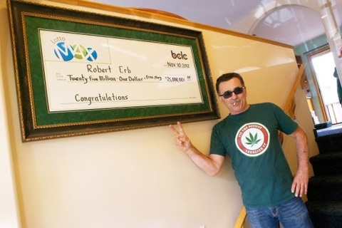 Canada Lotto Max Winner Bob Erb Smoking a Joint and Standing Next to Frame Oversized Cheque
